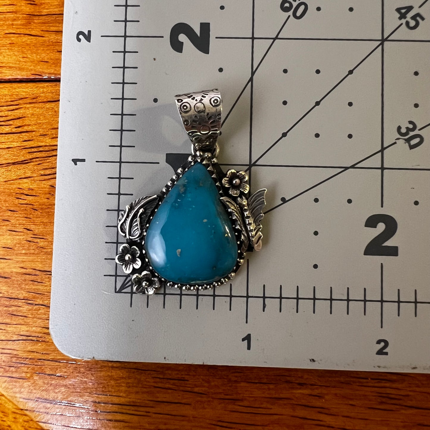 Kingman Turquoise Teardrop Pendant – Sterling Silver Floral Detail